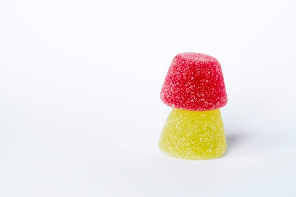 Stacked red and yellow sugar-coated gummies on a clean white background.